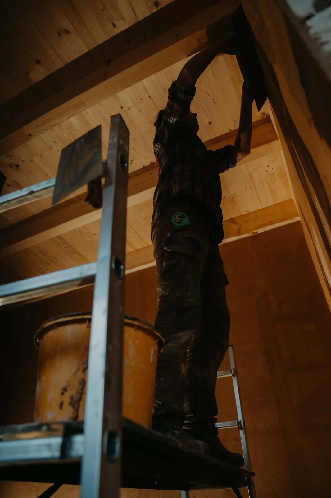 Denisa Divoká plastering a ceiling from a ladder