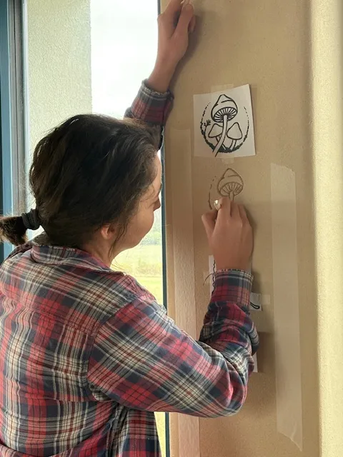 Denisa Divoká applying a stencil to a clay wall